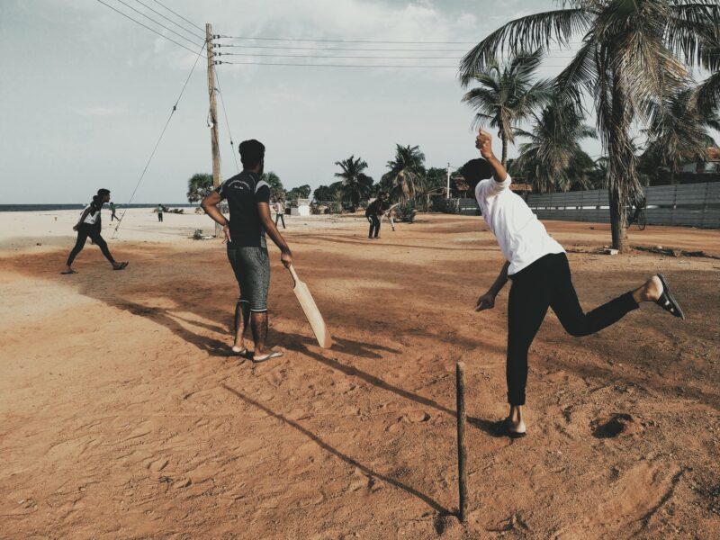 men playing cricket at beach