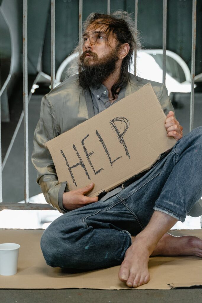 War Like Situation, a male beggar sitting on a ground while holding a help banner